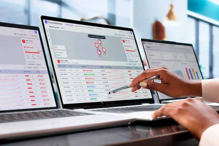 Analyst pointing to automated device health monitoring software dashboard on a laptop